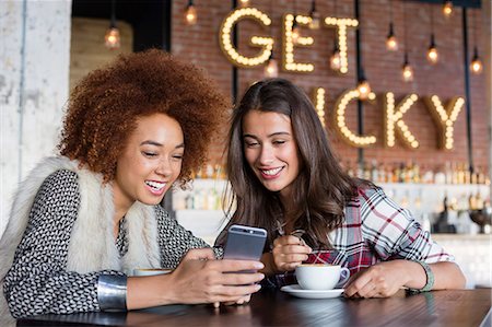 fluorescent (color) - Female friends using a smart phone with coffee at cafe Foto de stock - Sin royalties Premium, Código: 6108-08725353