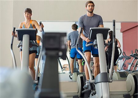 Young man and woman exercising on machines in a gym Stock Photo - Premium Royalty-Free, Code: 6108-08725358