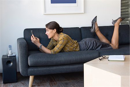 Happy businesswoman using a mobile phone on couch Stock Photo - Premium Royalty-Free, Code: 6108-08725368