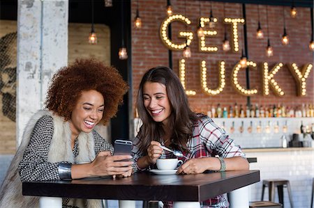 friends enjoying pictures - Female friends using a smart phone with coffee at cafe Stock Photo - Premium Royalty-Free, Code: 6108-08725397