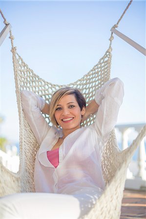 simsearch:6108-08943418,k - Pretty woman leaning in Hammock, smiling at camera Photographie de stock - Premium Libres de Droits, Code: 6108-08943528