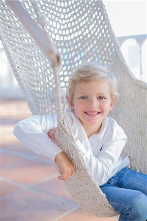 simsearch:6108-08943418,k - Portrait of a cute boy in a hammock outdoors smiling at camera Photographie de stock - Premium Libres de Droits, Code: 6108-08943535