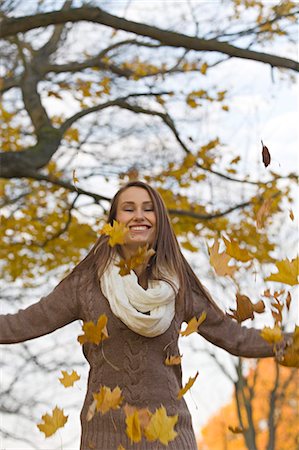 simsearch:6108-08943515,k - Portrait of a content young woman jumping with leaves in the park in Autumn Foto de stock - Sin royalties Premium, Código: 6108-08908947