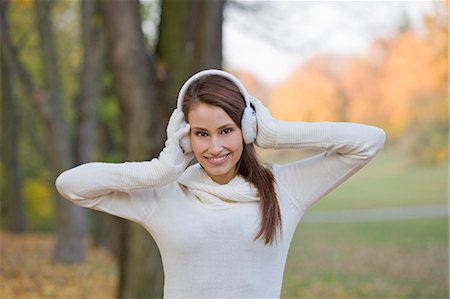 simsearch:6108-08943515,k - Portrait of a beautiful young woman with earmuffs smiling in the park in Autumn Foto de stock - Sin royalties Premium, Código: 6108-08908948