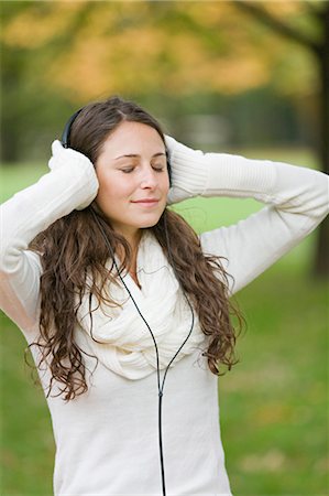 Portrait of a woman with closed eyes listening to music in the park in Autumn Stock Photo - Premium Royalty-Free, Code: 6108-08908939