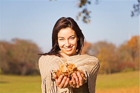 Portrait of a woman with leafes in Park smiling at camera Stock Photo - Premium Royalty-Free, Code: 6108-08909046