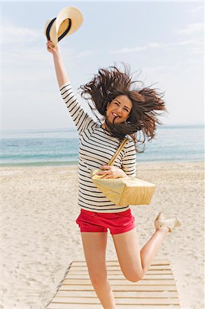 simsearch:6108-08908832,k - Young brunette woman jumping of happiness arriving at the beach Fotografie stock - Premium Royalty-Free, Codice: 6108-08909075