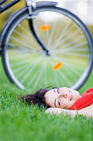 Woman with bicycle lying down in the park Stock Photo - Premium Royalty-Free, Code: 6108-08909033
