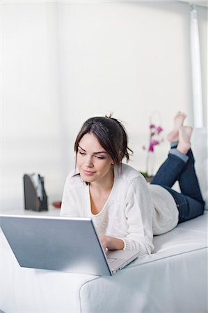 simsearch:6108-08909699,k - Beautiful brunette woman on a couch with computer Foto de stock - Royalty Free Premium, Número: 6108-08909140