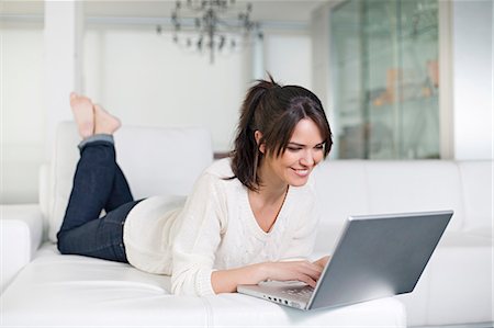 simsearch:6108-08909041,k - Beautiful brunette woman on a couch with computer Stock Photo - Premium Royalty-Free, Code: 6108-08909138