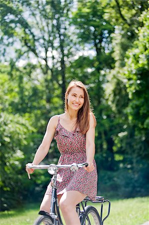 sich herumwälzen - Pretty woman riding a bike in the park Stockbilder - Premium RF Lizenzfrei, Bildnummer: 6108-08909277