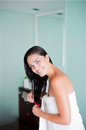 drying - Brunette woman brushing her hair and smiling at camera Stock Photo - Premium Royalty-Free, Code: 6108-08909574