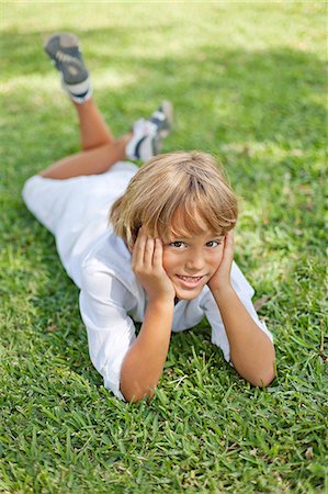 simsearch:877-06833417,k - Cute blonde boy lying down on grass in park smiling at camera Stock Photo - Premium Royalty-Free, Code: 6108-08909535