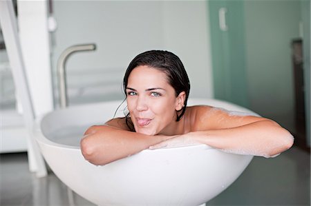 Young pretty brunette woman enjoying a bath and sticking out the tongue Stock Photo - Premium Royalty-Free, Code: 6108-08909615