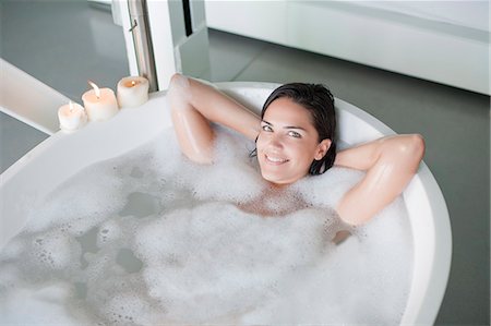 simsearch:6108-08909555,k - Young pretty brunette woman enjoying a bath and smiling at camera Foto de stock - Sin royalties Premium, Código: 6108-08909619