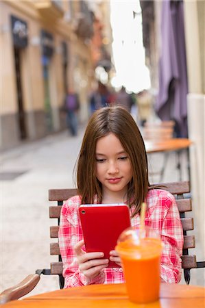 11 years old girl with Tablet and Juice at a Cafe Stock Photo - Premium Royalty-Free, Code: 6108-08909817