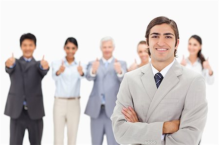 simsearch:6109-06002847,k - Close-up of a multicultural business team with their thumbs-up focus on a smiling man with his arms folded in foreground Foto de stock - Royalty Free Premium, Número: 6109-06002667