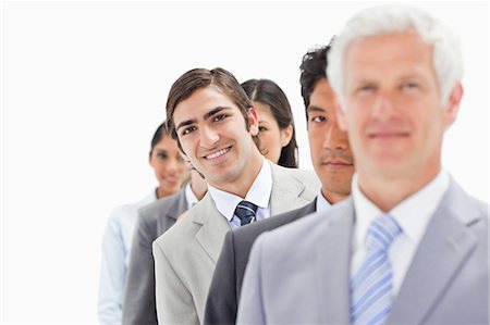 Close-up of a single line of smiling business people with focus on the third person against white background Stock Photo - Premium Royalty-Free, Code: 6109-06002759