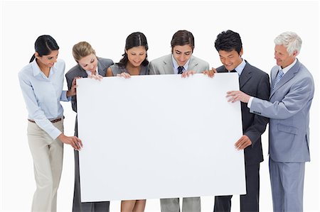 sales team - Close-up of a multicultural business team holding a big white placard against white background Stock Photo - Premium Royalty-Free, Code: 6109-06002771