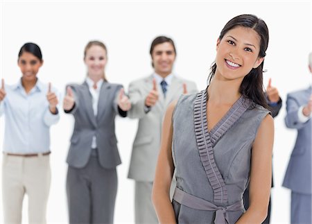 Woman with a business team behind her with their thumbs-up against white background Foto de stock - Sin royalties Premium, Código: 6109-06002777