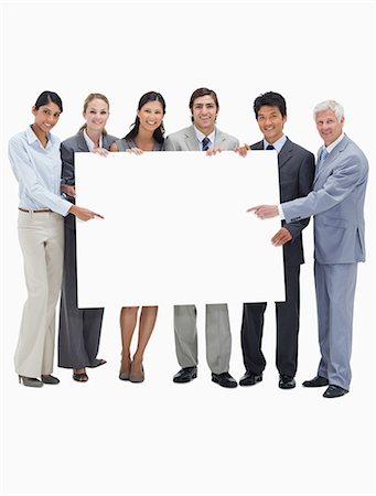 Smiling multicultural business team holding and showing a placard against white background Stock Photo - Premium Royalty-Free, Code: 6109-06002775