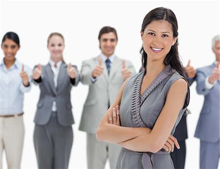 Smiling woman with a business team behind her with their thumbs-up against white background Stock Photo - Premium Royalty-Free, Code: 6109-06002778