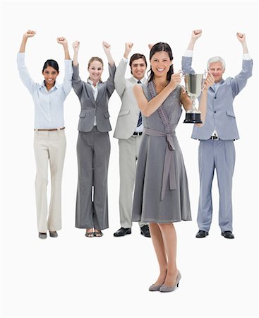 people holding trophies - Girl holding a cup with a business team raising their arms against white background Stock Photo - Premium Royalty-Free, Code: 6109-06002787