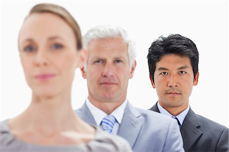 Close-up of a woman with two men behind her with focus on the last person against white background Foto de stock - Royalty Free Premium, Número: 6109-06002732