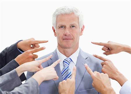 pointing finger - Serious businessman with fingers being pointed at him from many directions against white background Stock Photo - Premium Royalty-Free, Code: 6109-06002845