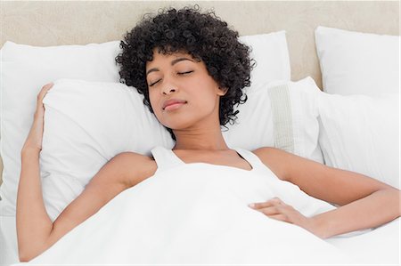 Curly haired woman sleeping peacefully in a white bed Fotografie stock - Premium Royalty-Free, Codice: 6109-06002875