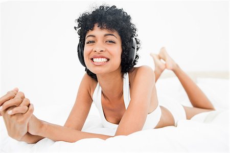 Femme aux cheveux crépuse, souriant d'une oreille à l'autre tout en musique Photographie de stock - Premium Libres de Droits, Code: 6109-06002912