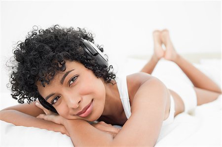 simsearch:6109-06002938,k - Portrait d'une femme aux cheveux noire, écouter de la musique en position couchée sur son lit Photographie de stock - Premium Libres de Droits, Code: 6109-06002914