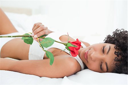 simsearch:6109-06002938,k - Femme aux cheveux crépuse, allongée sur son lit avec une rose dans une salle lumineuse Photographie de stock - Premium Libres de Droits, Code: 6109-06002920