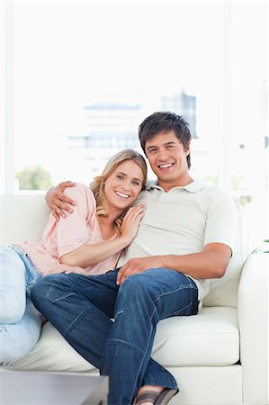 simsearch:6109-06003135,k - Ein Mann sitzt lächelnd, während die lächelnde Frau vor ihm auf der Couch liegt. Stockbilder - Premium RF Lizenzfrei, Bildnummer: 6109-06003094
