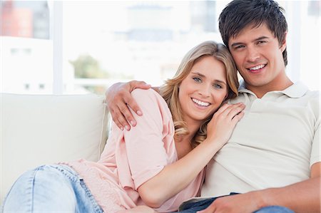 A man with his arm around her as she lies against him on the couch, both smiling Stock Photo - Premium Royalty-Free, Code: 6109-06003095