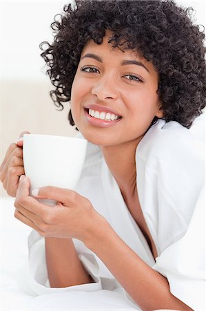 Portrait of a woman holding a cup of coffee while lying in her bed Stock Photo - Premium Royalty-Free, Code: 6109-06003011
