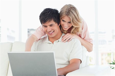 simsearch:6109-06003134,k - A man is sitting and using the laptop as the woman watches him from beside his head. Stock Photo - Premium Royalty-Free, Code: 6109-06003147