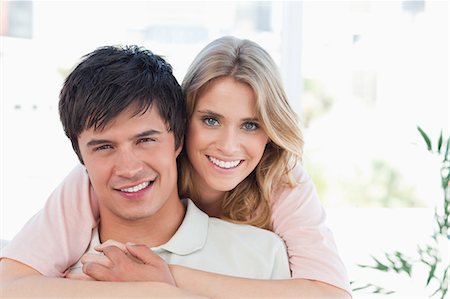 A man with the womans arms embracing him, both looking in front of them as they smile Stock Photo - Premium Royalty-Free, Code: 6109-06003153