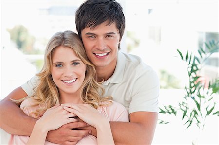 A man and woman hug, smile and hold hands while looking in front of them Stock Photo - Premium Royalty-Free, Code: 6109-06003161