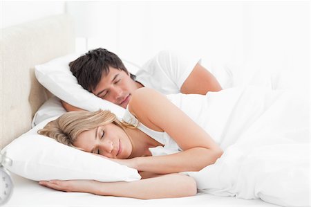 A man and woman with an arm under a pillow, sleeping in the bed together. Stock Photo - Premium Royalty-Free, Code: 6109-06003188