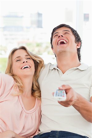 A close up shot of a man and woman laughing together at a television programme. Stock Photo - Premium Royalty-Free, Code: 6109-06003125