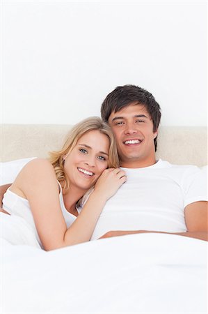 A close up shot of a man and woman in bed as she lies her head on his shoulder, they both smile. Stock Photo - Premium Royalty-Free, Code: 6109-06003265