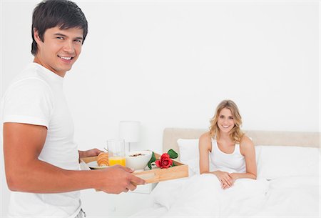 simsearch:6109-06003220,k - L'homme apporte à la femme un petit déjeuner au lit, et tous deux sont souriant. Photographie de stock - Premium Libres de Droits, Code: 6109-06003272