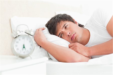 A man waking up hearing his alarm clock and looking sad. Fotografie stock - Premium Royalty-Free, Codice: 6109-06003287