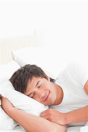 A man with his head resting on the pillow, smiling softly, Stock Photo - Premium Royalty-Free, Code: 6109-06003284