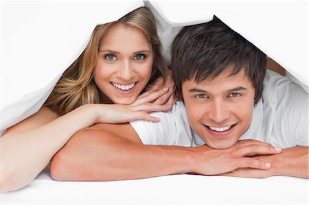 simsearch:6109-06003220,k - Un homme et une femme se reposer sur leurs mains, souriant et heureux sous une couette. Photographie de stock - Premium Libres de Droits, Code: 6109-06003226