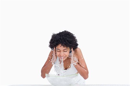 face washing - Relaxed young woman splashing her face with water against a white background Foto de stock - Sin royalties Premium, Código: 6109-06003358