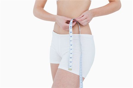 Waist being measured by a measuring tape against a white background Stock Photo - Premium Royalty-Free, Code: 6109-06003362