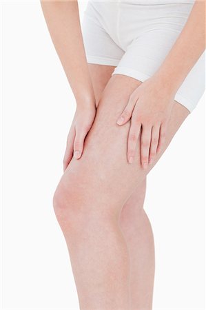 robinetterie - Femme en slip masser sa cuisse contre un fond blanc Photographie de stock - Premium Libres de Droits, Code: 6109-06003366