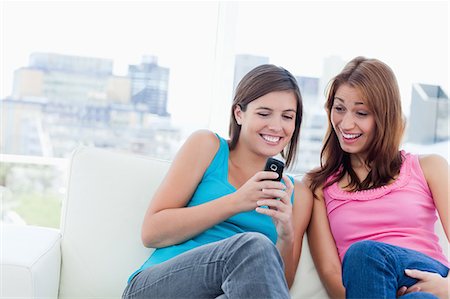 phone young caucasian woman relaxed - Smiling teenager showing a text on her phone to her friend Stock Photo - Premium Royalty-Free, Code: 6109-06003311